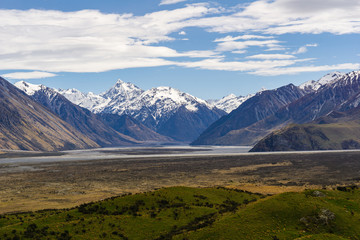 Vast valley with mountains on the horizon, snowy mountain peaks, during sunny cloudy day