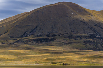 Minimalist landscape with brown steep hill during warm but cloudy day