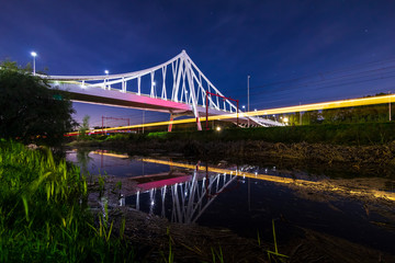 Suspension bridge at night under moonlight with light trails