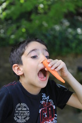 Playful boy making nose with peeled carrot