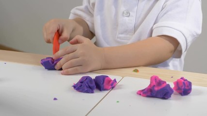 A two years old preschool child playing with modeling clay (compound). Smiling and looking at the camera. Early childhood education to children concept