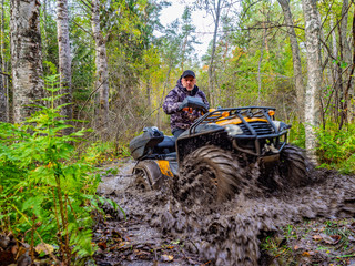A man rides on ATV through the mud. Riding a quad bike. A man rides an all-terrain vehicle. Riding off-road on an ATV. Outdoor activity. Extreme. Rent a quad bike.