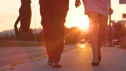 LOW ANGLE: Unrecognizable man and woman in high heels walking to work at sunrise