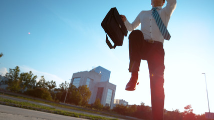 BOTTOM UP: Businessman in a hurry jumps over the camera as he runs to office.