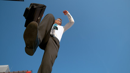 BOTTOM UP: Cheerful businessman jumps over the camera after getting promoted.