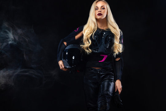 Fashion model DJ and biker in headphones, black leather jacket, leather pants, stylish pretty blonde woman in night casual outfit. Long wavy hairstyle.