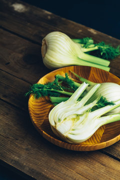 Fresh fennel bulbs in plate on wooden background.