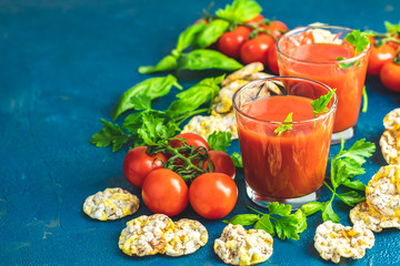 Red cocktail with tomato juice between tomatoes, basil, parsley and nutritious cereal breads