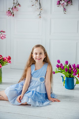 Portrait of a beautiful blue-eyed girl, a little girl among spring flowers in a bright room.