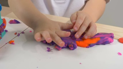 A two years old preschool child playing with modeling clay (compound). Smiling and looking at the camera. Early childhood education to children concept