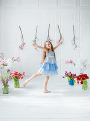 Portrait of a beautiful blue-eyed girl, a little girl among spring flowers in a bright room.