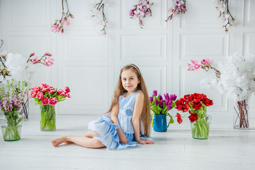 Portrait of a beautiful blue-eyed girl, a little girl among spring flowers in a bright room.