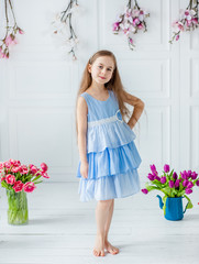 Portrait of a beautiful blue-eyed girl, a little girl among spring flowers in a bright room.