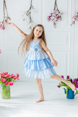 Portrait of a beautiful blue-eyed girl, a little girl among spring flowers in a bright room.