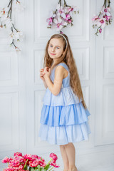 Portrait of a beautiful blue-eyed girl, a little girl among spring flowers in a bright room.