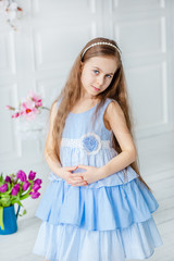 Portrait of a beautiful blue-eyed girl, a little girl among spring flowers in a bright room.