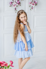 Portrait of a beautiful blue-eyed girl, a little girl among spring flowers in a bright room.