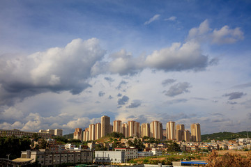 Residential and Commercial buildings in Kunming, Yunnan Province China. Miscellaneous city skyscrapers, skyline with white clouds and blue sky. Cluster of tall buildings at the edge of the city.