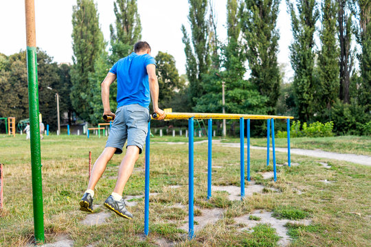 Fit man doing calisthenics workout balancing on parallel horizontal bars exercise in outdoor park in Rivne, Ukraine playground