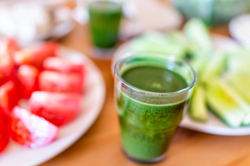 Fresh sliced juicy ripe red tomatoes slices on plate with closeup of green juice on wooden table as healthy snack or salad appetizer