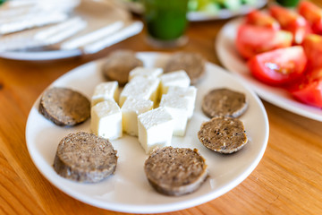 Closeup of lunch dinner plate appetizer with vegan vegetarian sausage slices and cheese cubes and chopped tomatoes
