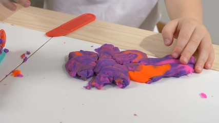 A two years old preschool child playing with modeling clay (compound). Smiling and looking at the camera. Early childhood education to children concept