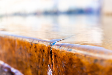 Detail macro abstract closeup of golden stone water fountain surface in park with bokeh by mermaid statue in Warsaw, Poland