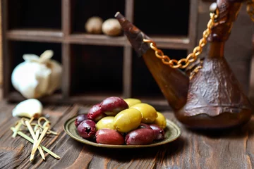 Foto op Plexiglas Olives in a bronze platel on a wooden kitchen table © ferumov