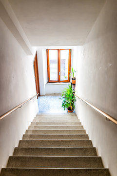 Vertical View Of Hall Interior In Italian Apartment Home With Window And Green Plants Looking Down High Angle Above Steps Stairs In Hallway