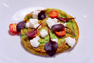 Omelet with vegetables cheese and tomatoes on white plate