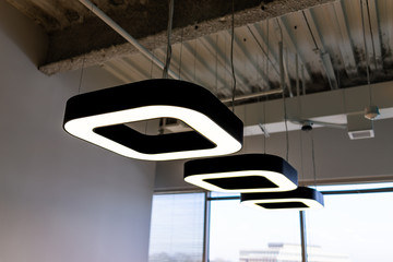 New modern office room in building with corporate business ceiling closeup of row of many square contemporary lights