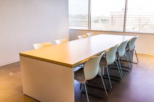 New modern office room in building with closeup of wooden meeting corporate business table by glass window and many chairs empty nobody