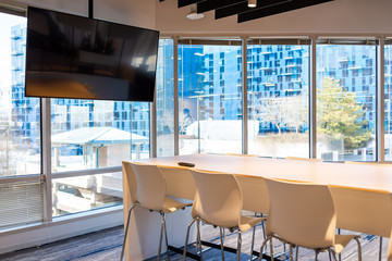 Modern office in building with wooden meeting corporate business table with television screen and chairs empty nobody
