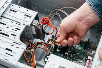 Hand of man plugging SATA (Serial AT Attachment, Serial ATA) data cable in hard drive device....