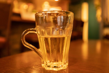 Glass half empty or half full sits on wooden table with blurred background