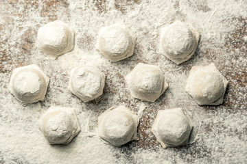 Uzbek national food Chuchvara, like dumplings, on a wooden board, in flour