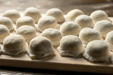 Uzbek national food Chuchvara, like dumplings, on a wooden board, in flour