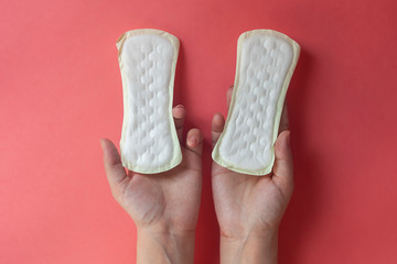 Woman's hands holding two feminine hygiene pads. Hands of female hold menstrual pads or sanitary napkins for women