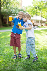 Two boys hugging one another or fighting jokingly while drinking cocoa outdoors