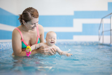 Young woman and her baby daughter in indoor swimming pool