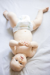 Cute baby girl looking at camera while lying down on bed at home