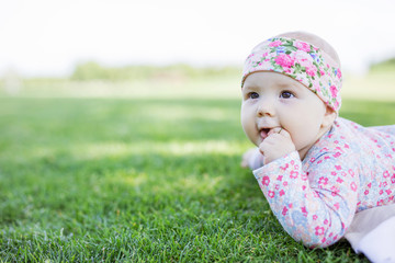 Cute baby girl looking up while lying down on grass in park and