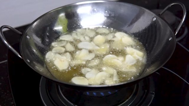 Healthy food. Frying garlic chips in a pan with hot olive oil.