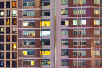 Fototapeta na wymiar City apartment windows at night. Residential highrise residences for metro housing in urban environment.