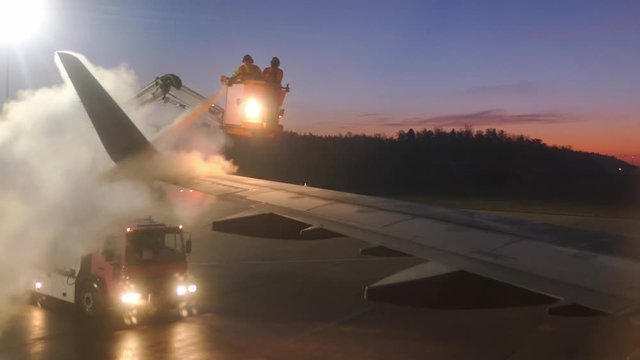 Aircraft De-Icing by Airport Ground Crew in De-Icing Truck at Dawn