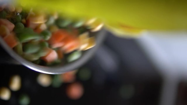 Slow. Motion shot of mixed vegetables being poured from aa yellow bag into a pot.