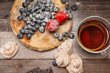 Healthy breakfast, tea and homemade pancakes with fresh berries on wooden table