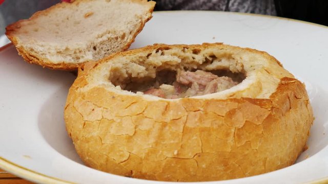 Food concept - Spoon stir soup. Pouring polish traditional soup called zur or white borscht into bread bowl.
