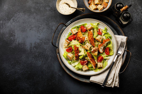 Caesar salad with Chicken breast meat on metal tray on dark background copy space