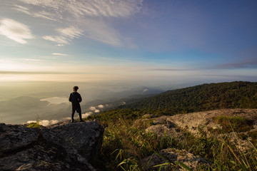 Fototapeta premium Silhouettes of man standing on top mountain and looking sunset.